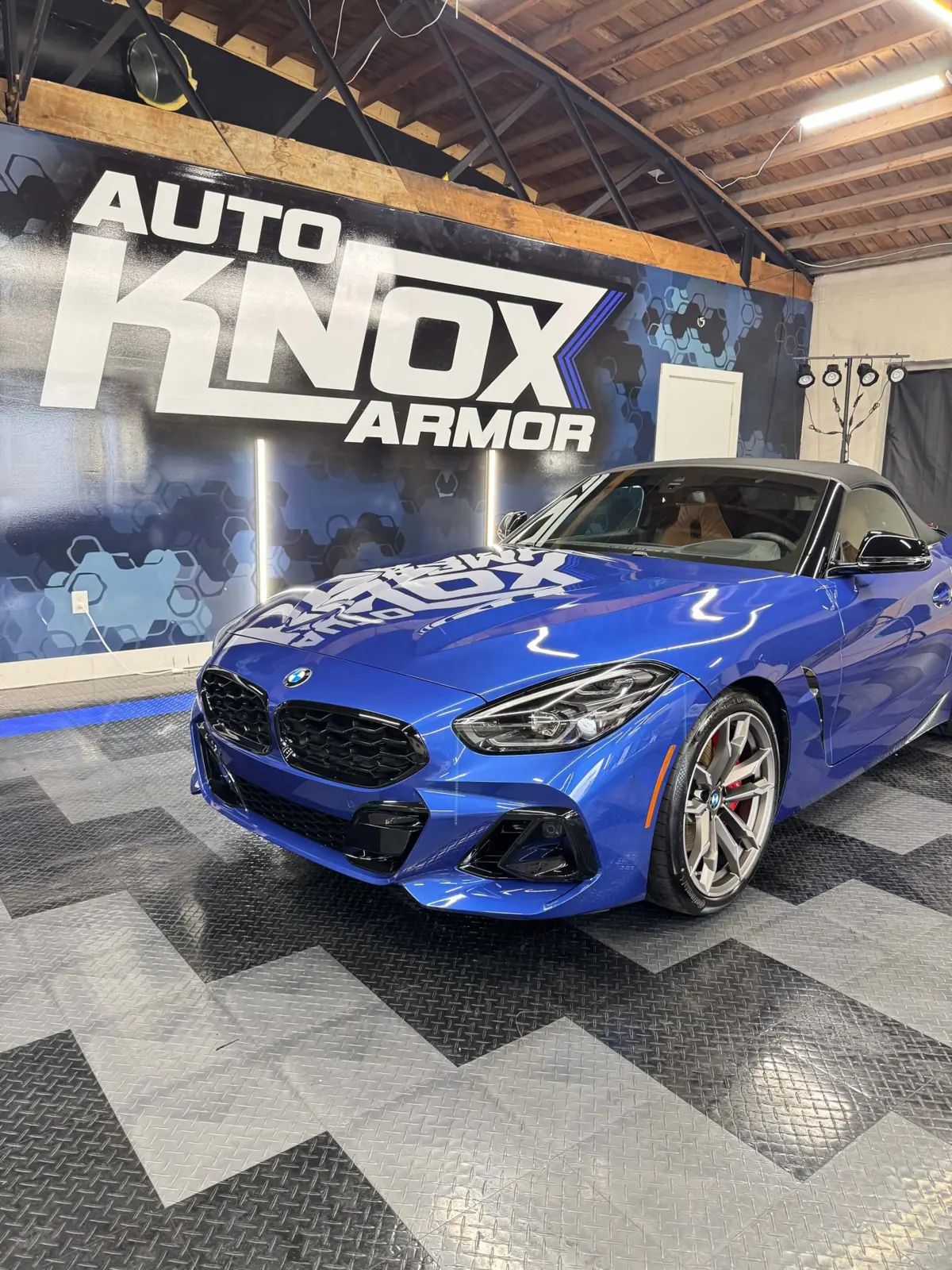 Blue BMW Z4 in front of the Auto Knox Armor wall in their Knoxville shop