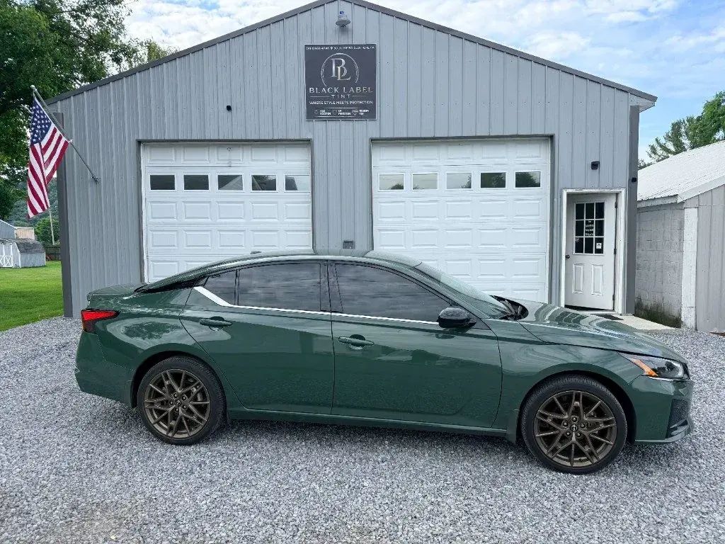 Green Nissan Altima outside Black Label Tint's two-bay shop
