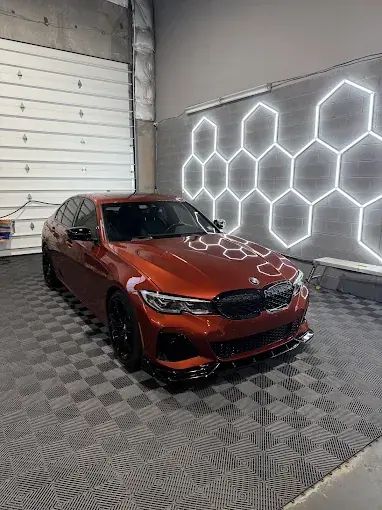 Orange BMW with window tint under hexagon shop lights
