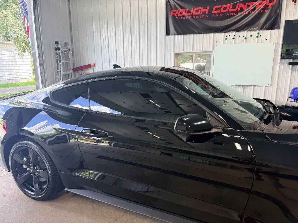 Black Mustang with tinted windows inside Black Label Tint's shop